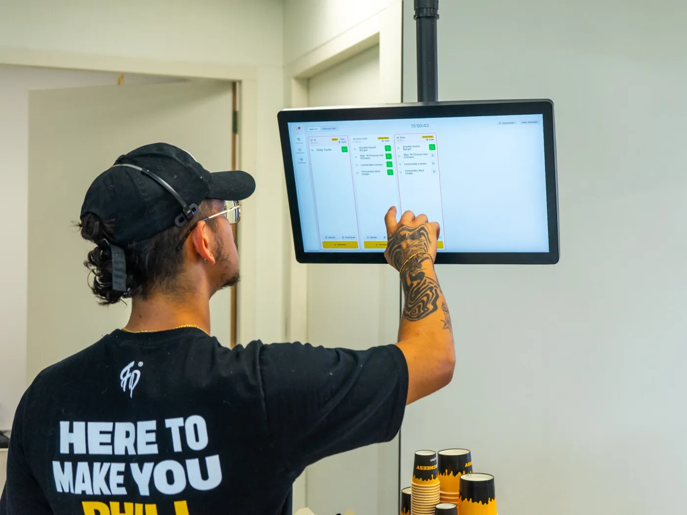 Un employé de Fat Phill's coche une commande Drive-Thru sur l'Écran Cuisine Onesix