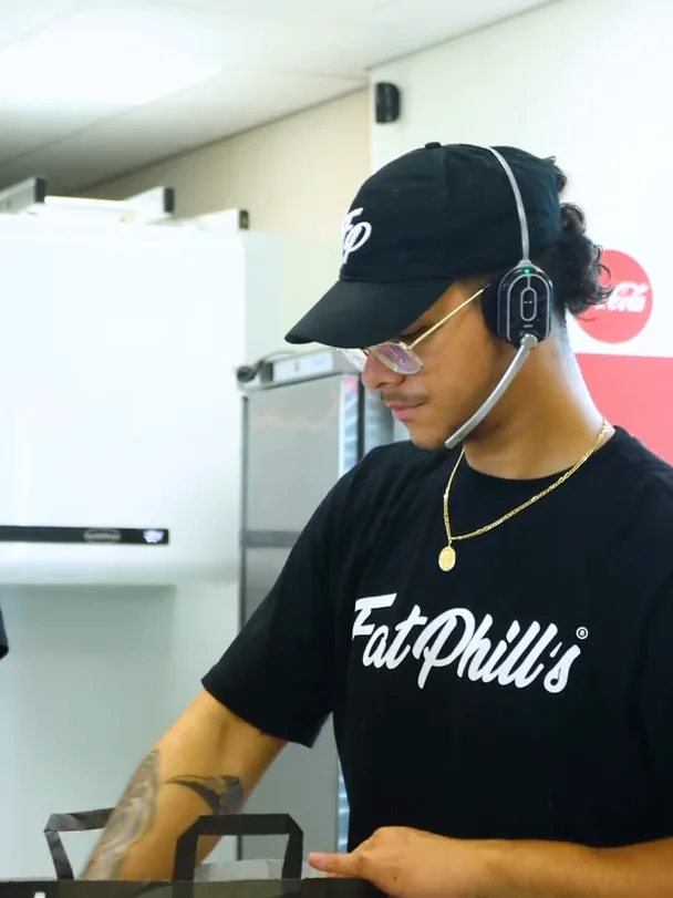 Un employé de Fat Phill's avec casque prépare une commande Drive-Thru