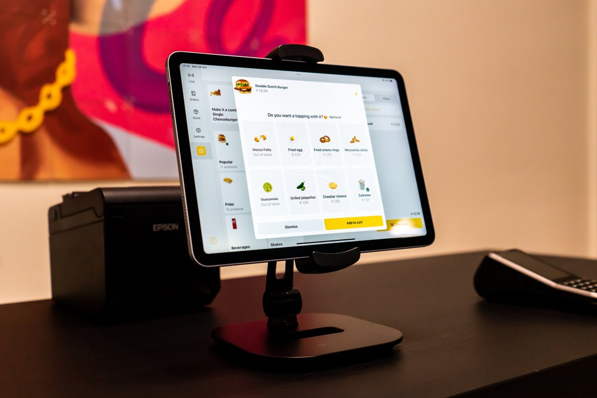 Caisse Onesix sur une tablette avec un écran d'upsell, à côté d'une imprimante à tickets et d'un terminal de paiement